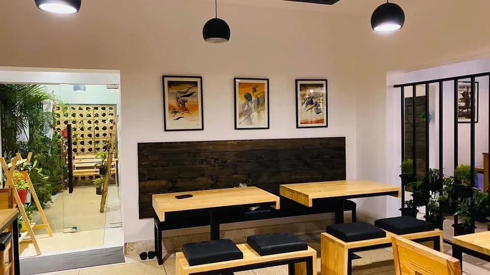 Wooden tables and benches under three framed paintings
