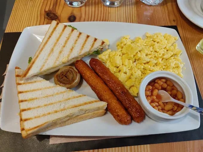 A breakfast plate with toast, sausages, scrambled eggs and baked beans