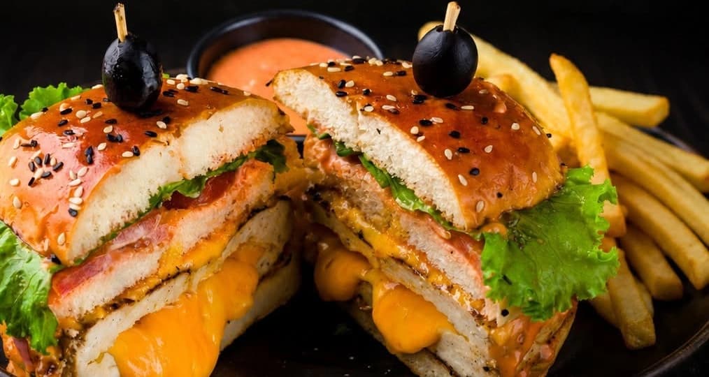Chicken Cheese Burger cut in half, with melted cheese, lettuce and chips