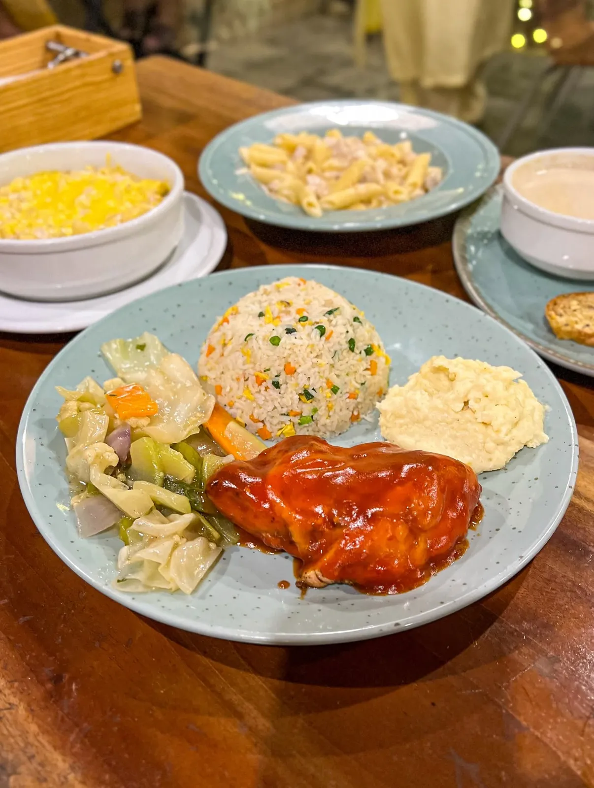 Chicken in a red sauce with fried rice, mashed potato and sautéed vegetables