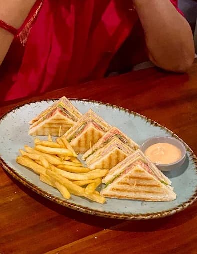 Club sandwich triangles with fries and a dip on a blue platter