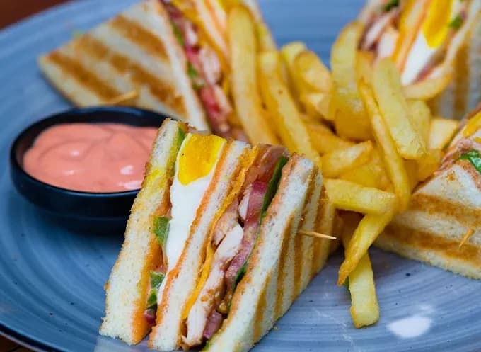 Club sandwich with egg, served with fries and a pink dip