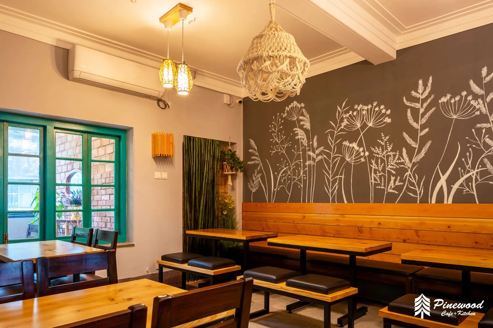 Wooden tables and benches in front of a grey wall painted with white grasses