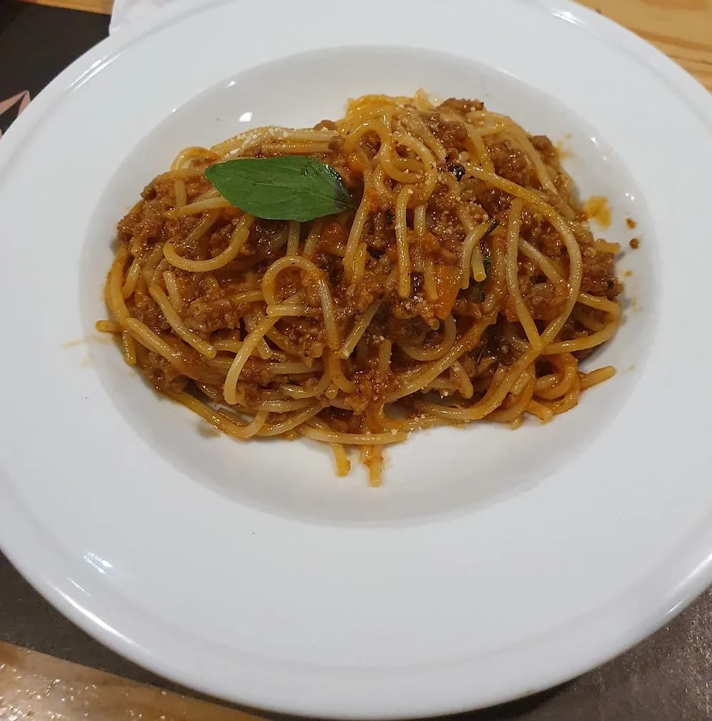 Spaghetti with a minced meat sauce and a basil leaf