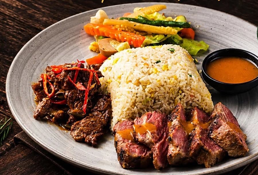 A set menu plate: sliced tenderloin steak, spicy beef curry, fried rice and vegetables